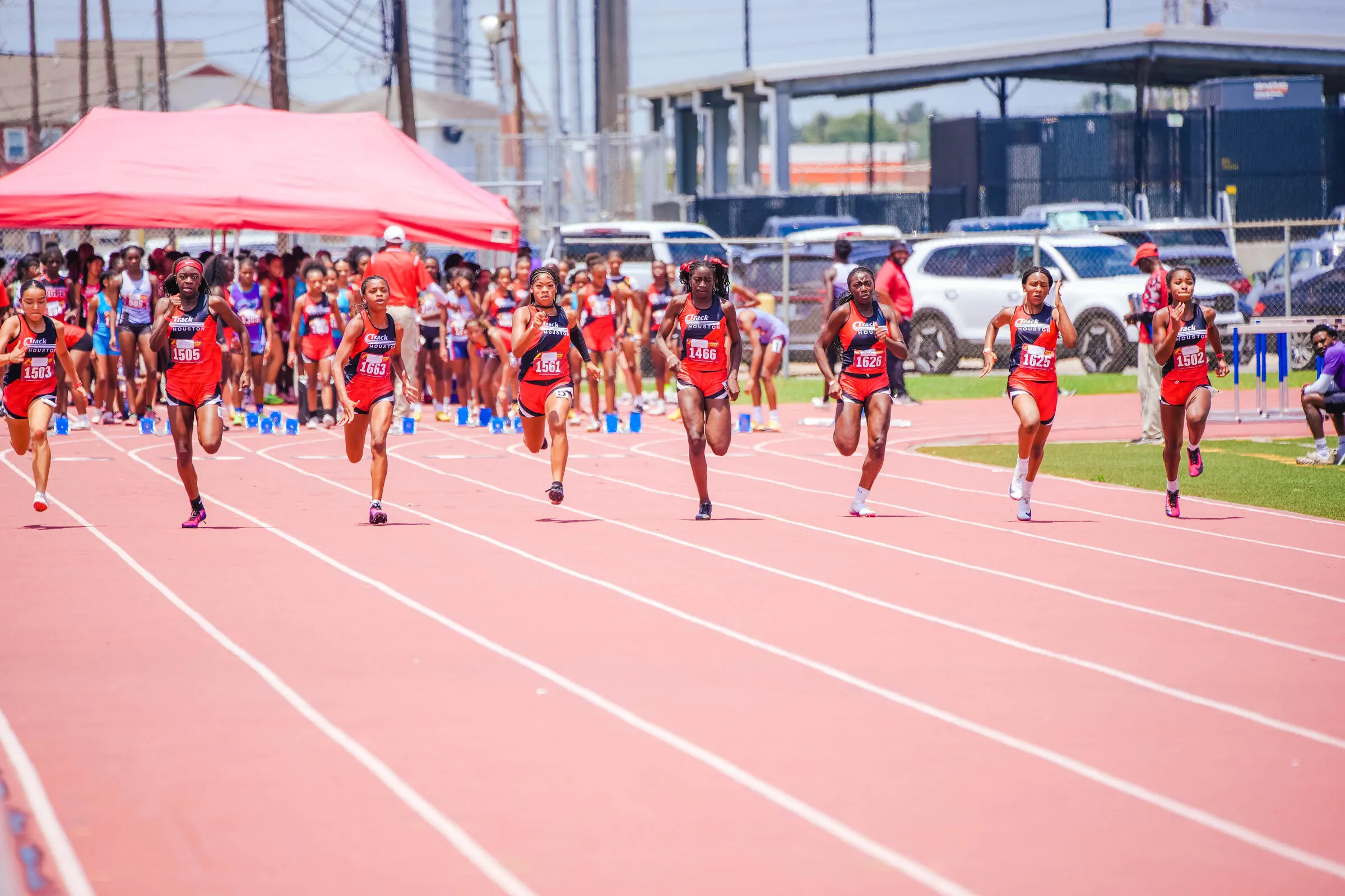 Eight Track Houston girls sprint off the start line in matching red and black uniforms.